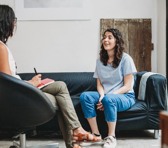 Sesión de psicoterapia, mujer joven hablando con su psicólogo en su consultorio sobre su salud conductual.