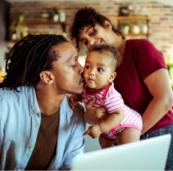 Familia joven en su sala de estar usando una computadora portátil.