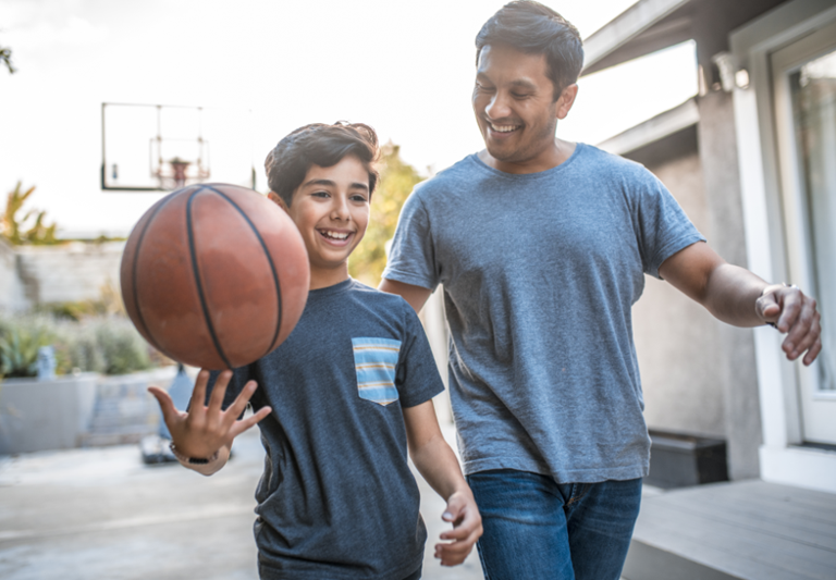 Muchacho feliz girando baloncesto mientras camina por el padre.
