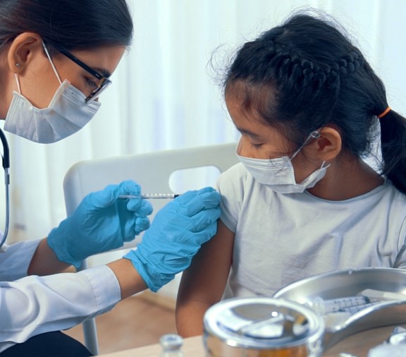 Niña recibiendo una vacuna de un pediatra