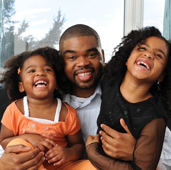 Padre afroamericano sonriendo con hijas.