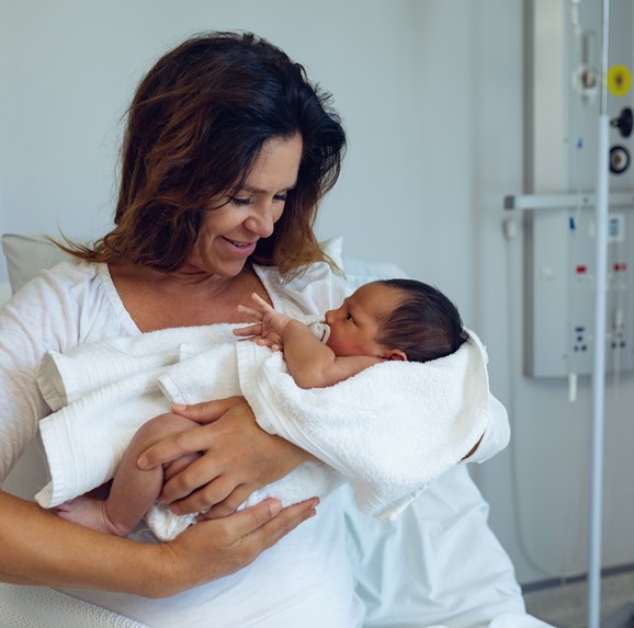 Nueva mamá con bebé en la cama del hospital