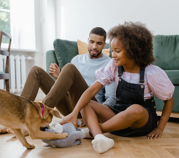 Niña jugando con perro mientras papá vigila